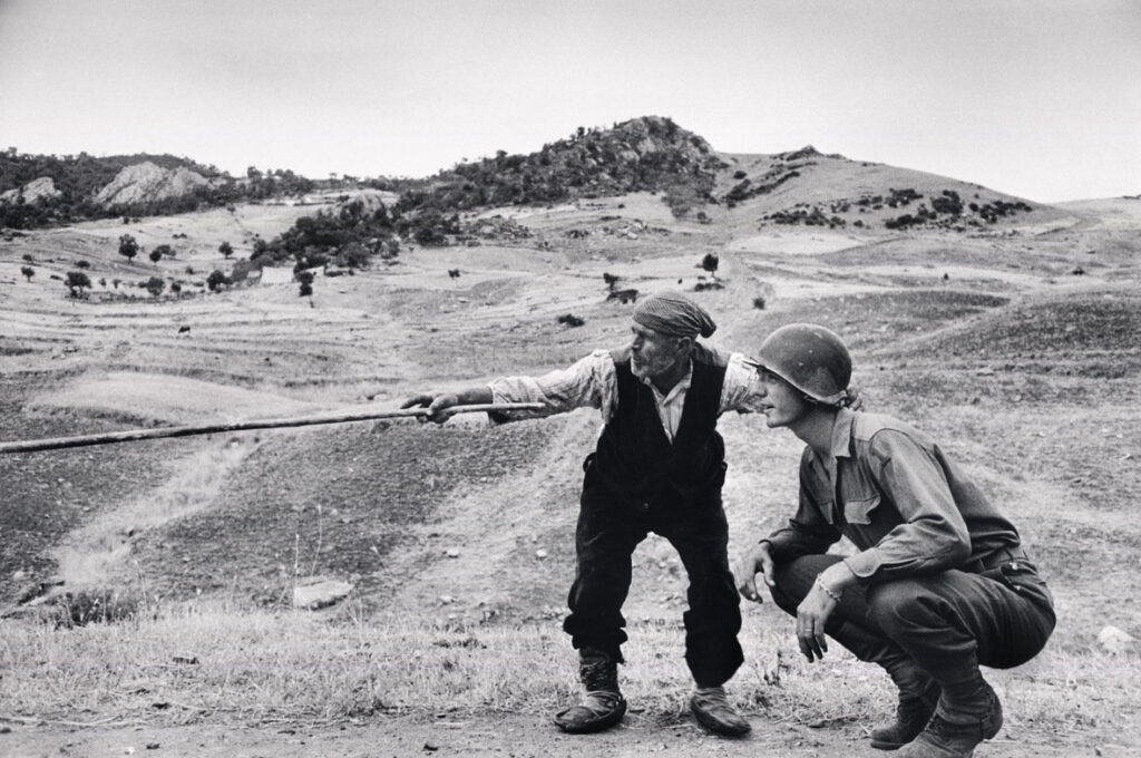 ITALY. Near Troina. August 4-5, 1943. Sicilian peasant telling an American officer which way the Germans had gone. ©Robert Capa © International Center of Photography / Magnum Photos